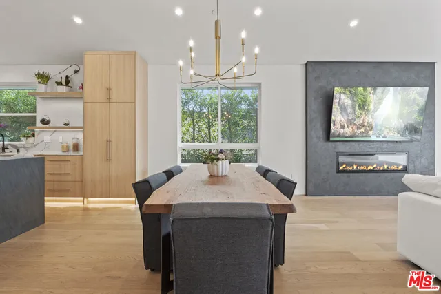 a kitchen with kitchen island a stove a refrigerator a sink and a dining table with wooden floor