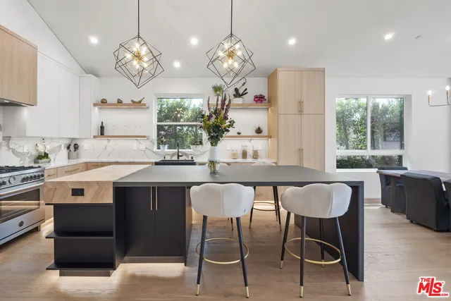 a kitchen with stainless steel appliances granite countertop a dining table chairs and a refrigerator