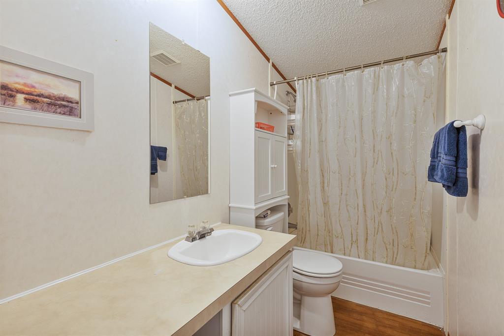 439 Slayden Road Sunset, TX 76270 - Photo 17 of 27 Bathroom featuring a wood-finish floor, white vanity with integrated sink, rectangular mirror, and an alcove tub with shower