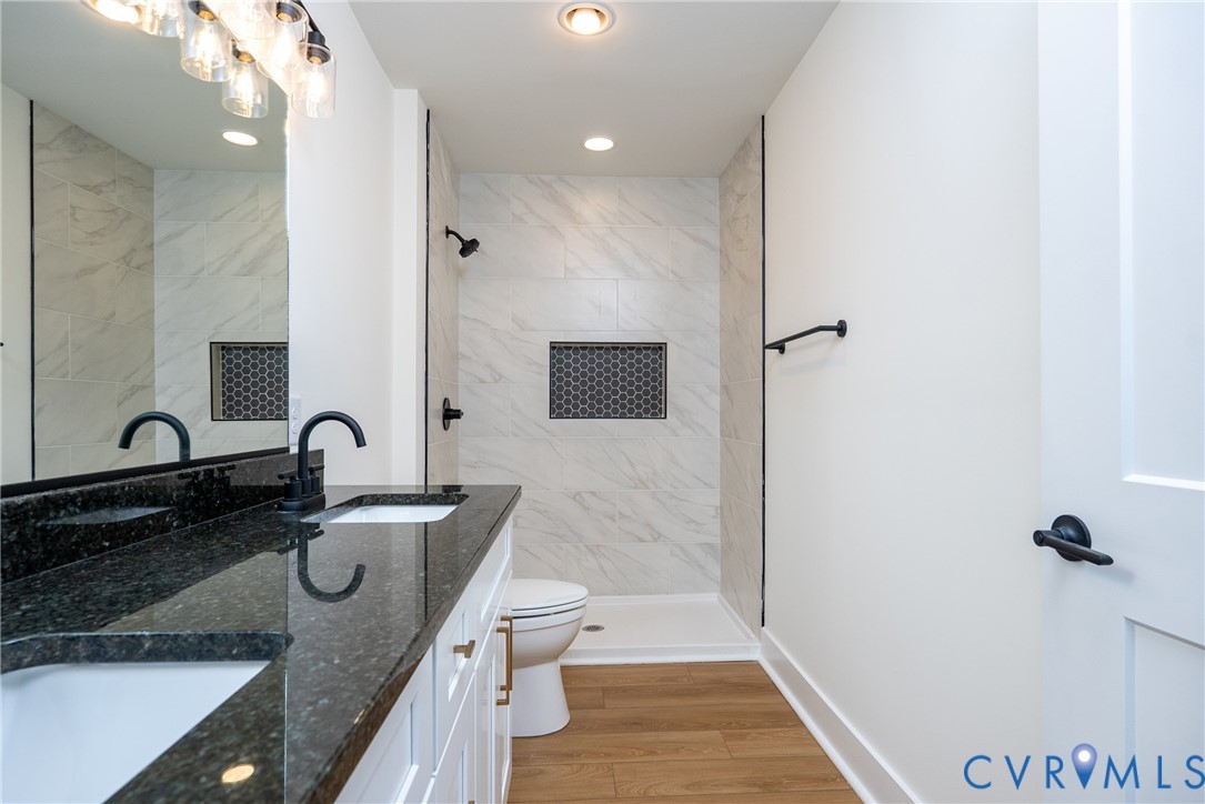 601 Mill Pond Drive Ruther Glen, VA 22546 - Photo 23 of 32 a bathroom with a granite countertop sink a toilet a mirror and shower