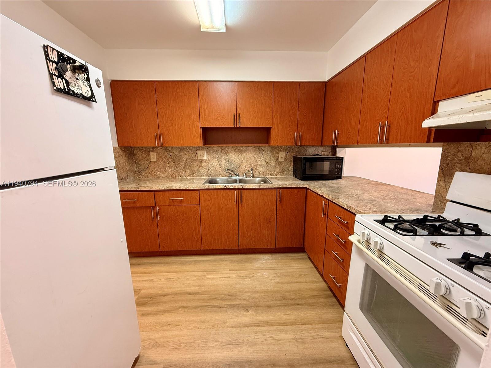 617 Northwest 10th Street Miami, FL 33136 - Photo 28 of 29 a kitchen with stainless steel appliances granite countertop a refrigerator a stove and a sink with wooden cabinets