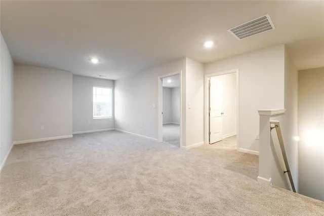 an empty room with windows and a refrigerator