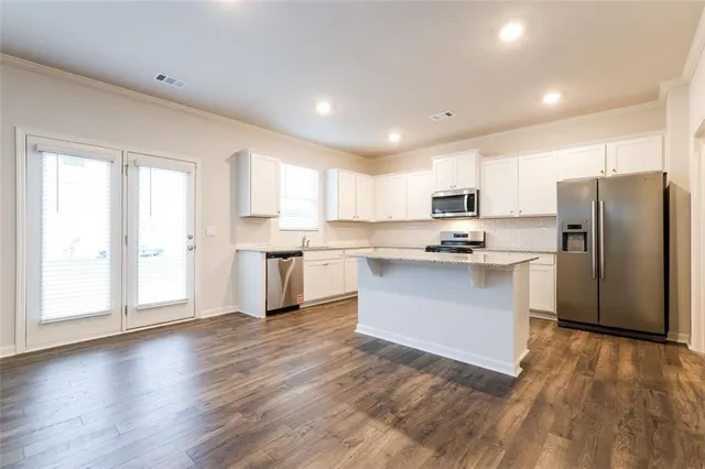 a kitchen with wooden floors and white stainless steel appliances
