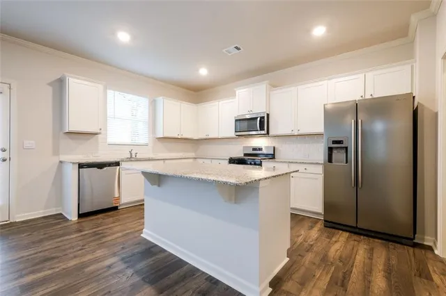 a kitchen with a refrigerator a sink dishwasher a stove and white cabinets with wooden floor