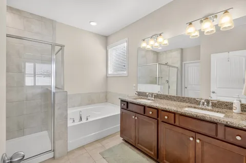 a bathroom with a granite countertop bathtub a sink and a large mirror