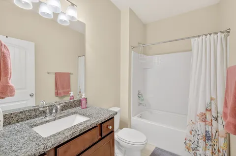 a bathroom with a granite countertop sink a mirror a bathtub and shower