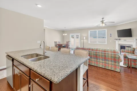 a kitchen with granite countertop kitchen island a sink dishwasher a dining table and chairs with wooden floor