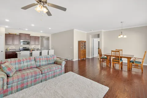 a living room with furniture and a dining table with wooden floor