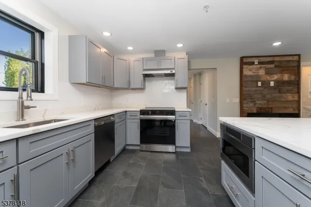 a kitchen with stainless steel appliances kitchen island granite countertop a stove sink and cabinets