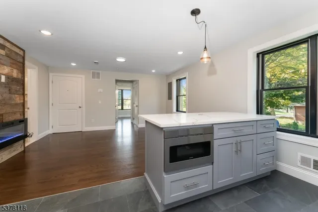 a kitchen with a stove and white cabinets with wooden floor