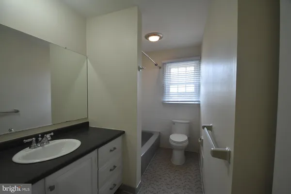 a bathroom with a granite countertop sink toilet and a mirror