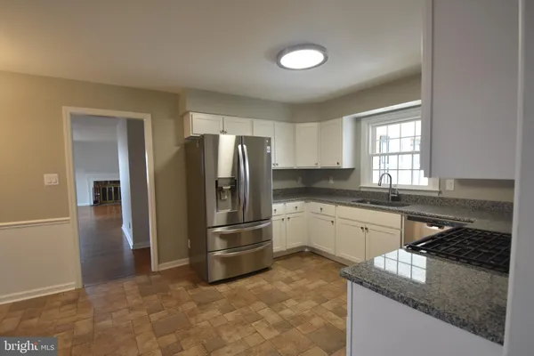 a kitchen with granite countertop a refrigerator and a stove top oven