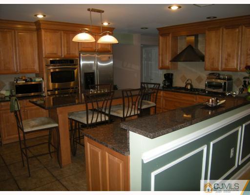 10 Sturgis Road Edison, NJ 08817 - Photo 5 of 9 a kitchen with kitchen island granite countertop a stove a sink a dining table and chairs with wooden floor