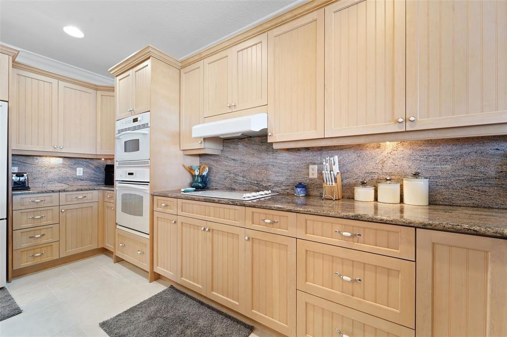 17735 Gulf Boulevard, Unit 702 Redington Shores, FL 33708 - Photo 13 of 60 a kitchen with granite countertop white cabinets and white appliances