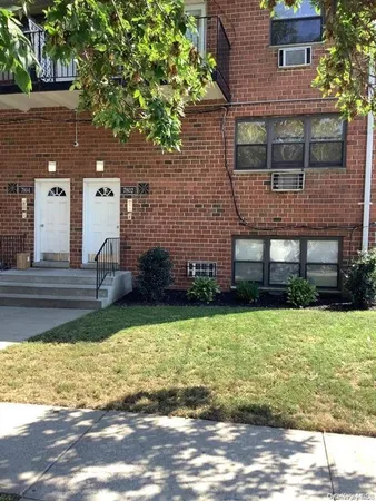 a house view with a sitting space garden and tall trees