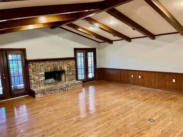 a view of empty room with wooden floor and fireplace