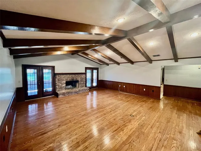 a view of an empty room with wooden floor and a fireplace