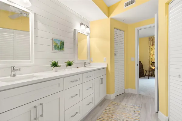 a spacious bathroom with a double vanity sink a mirror and a shower