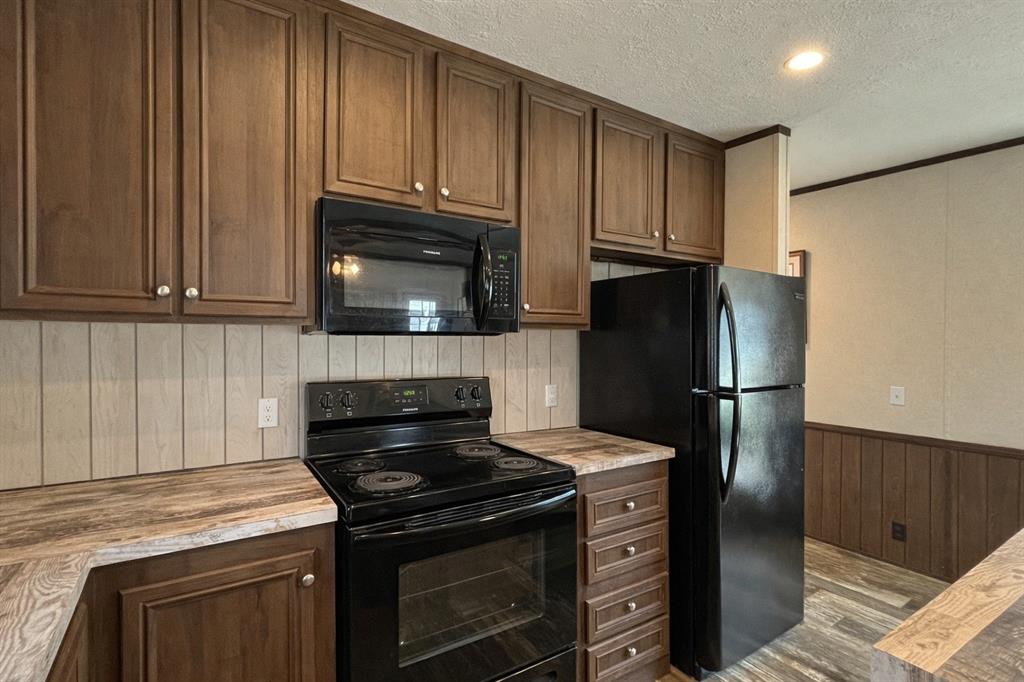 750 Waterfront Row Quitman, TX 75783 - Photo 11 of 32 a kitchen with granite countertop wooden cabinets and stainless steel appliances