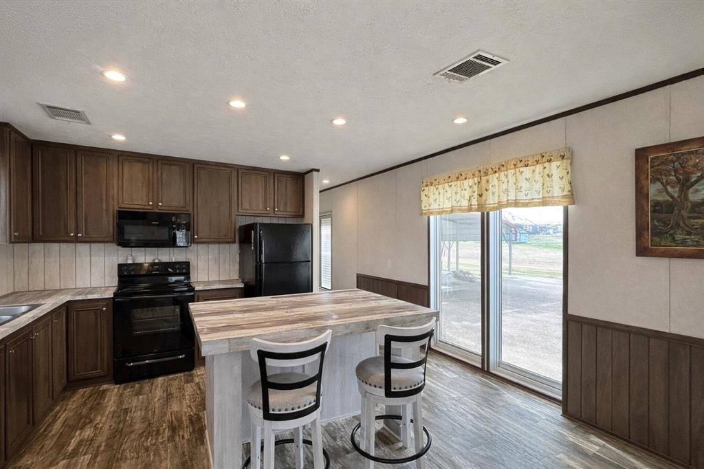 750 Waterfront Row Quitman, TX 75783 - Photo 8 of 32 a kitchen with stainless steel appliances granite countertop a stove a refrigerator a sink a dining table and chairs with wooden floor