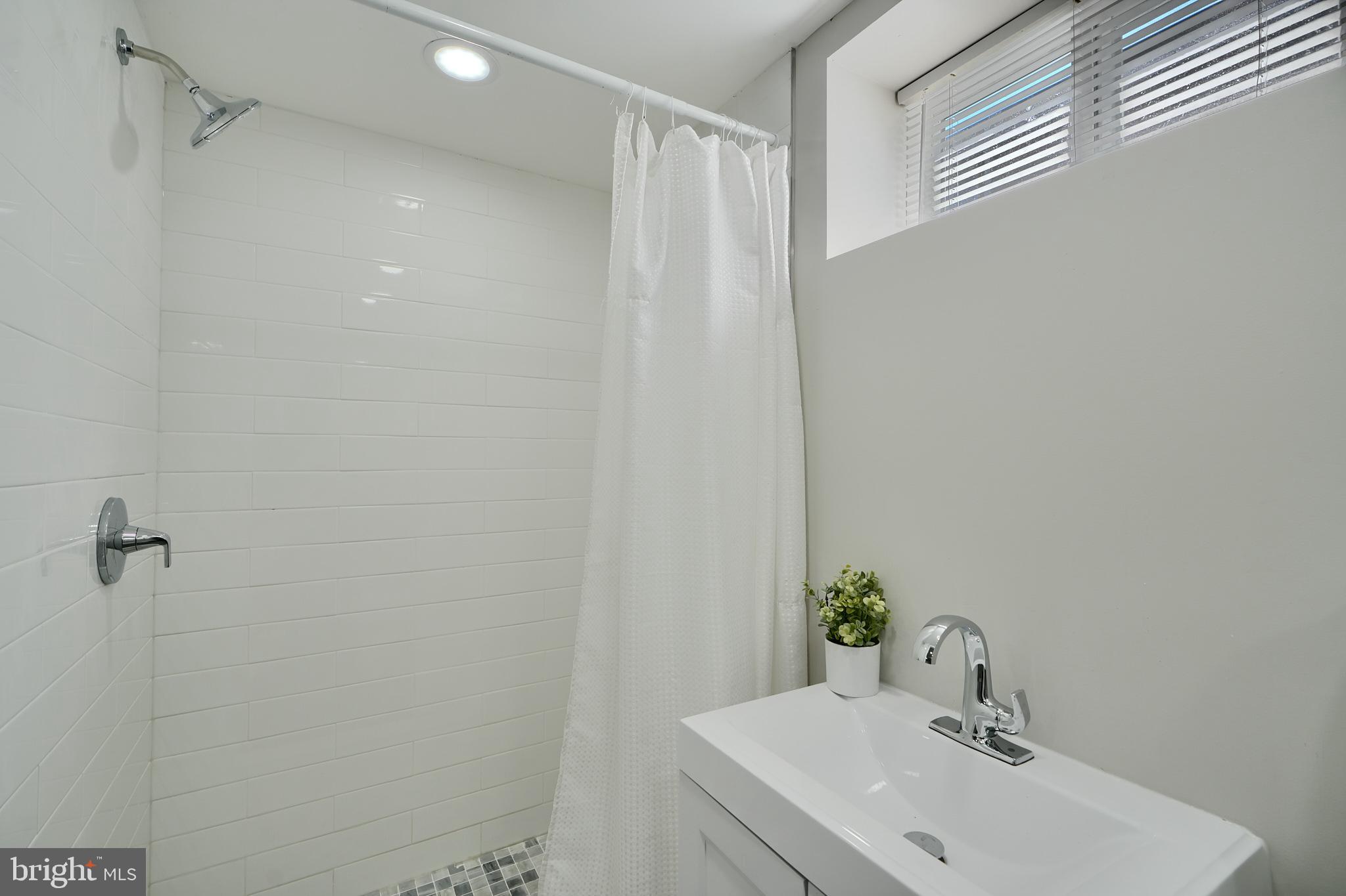 5805 Key Avenue Baltimore, MD 21215 - Photo 35 of 39 a bathroom with a sink a shower and a mirror