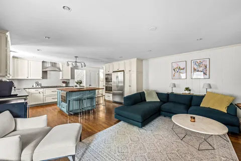 a living room with furniture wooden floor and kitchen view