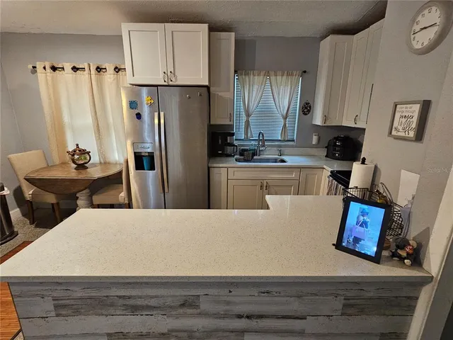 a kitchen with stainless steel appliances kitchen island granite countertop a refrigerator a stove a sink dishwasher and white cabinets with wooden floor