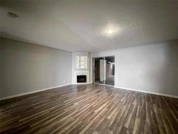 a view of empty room with wooden floor and fireplace