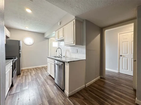 a kitchen with granite countertop stainless steel appliances a sink a stove and cabinets