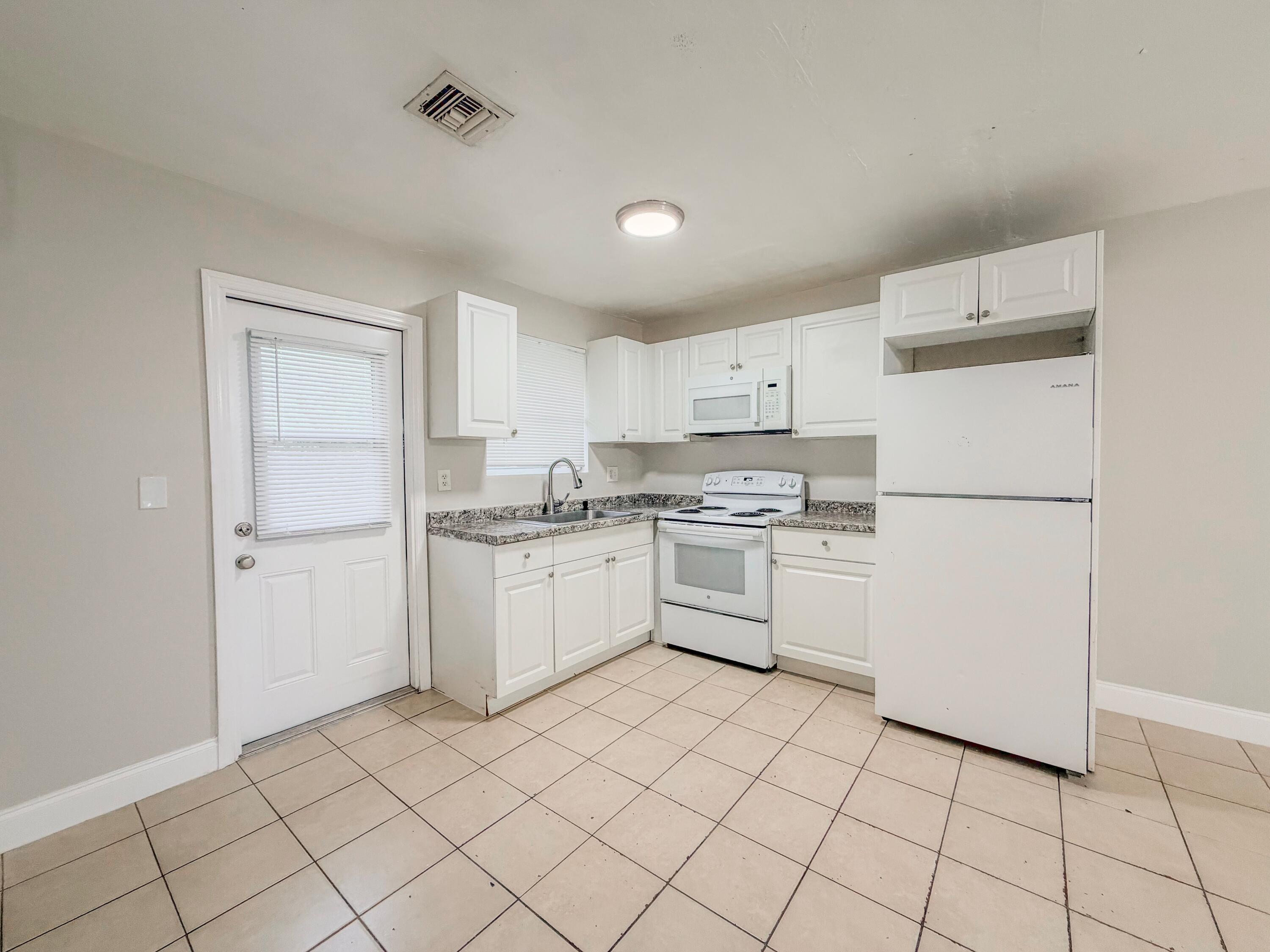 3077 Floweva Street Palm Springs, FL 33406 - Photo 3 of 12 a kitchen with white cabinets and white appliances