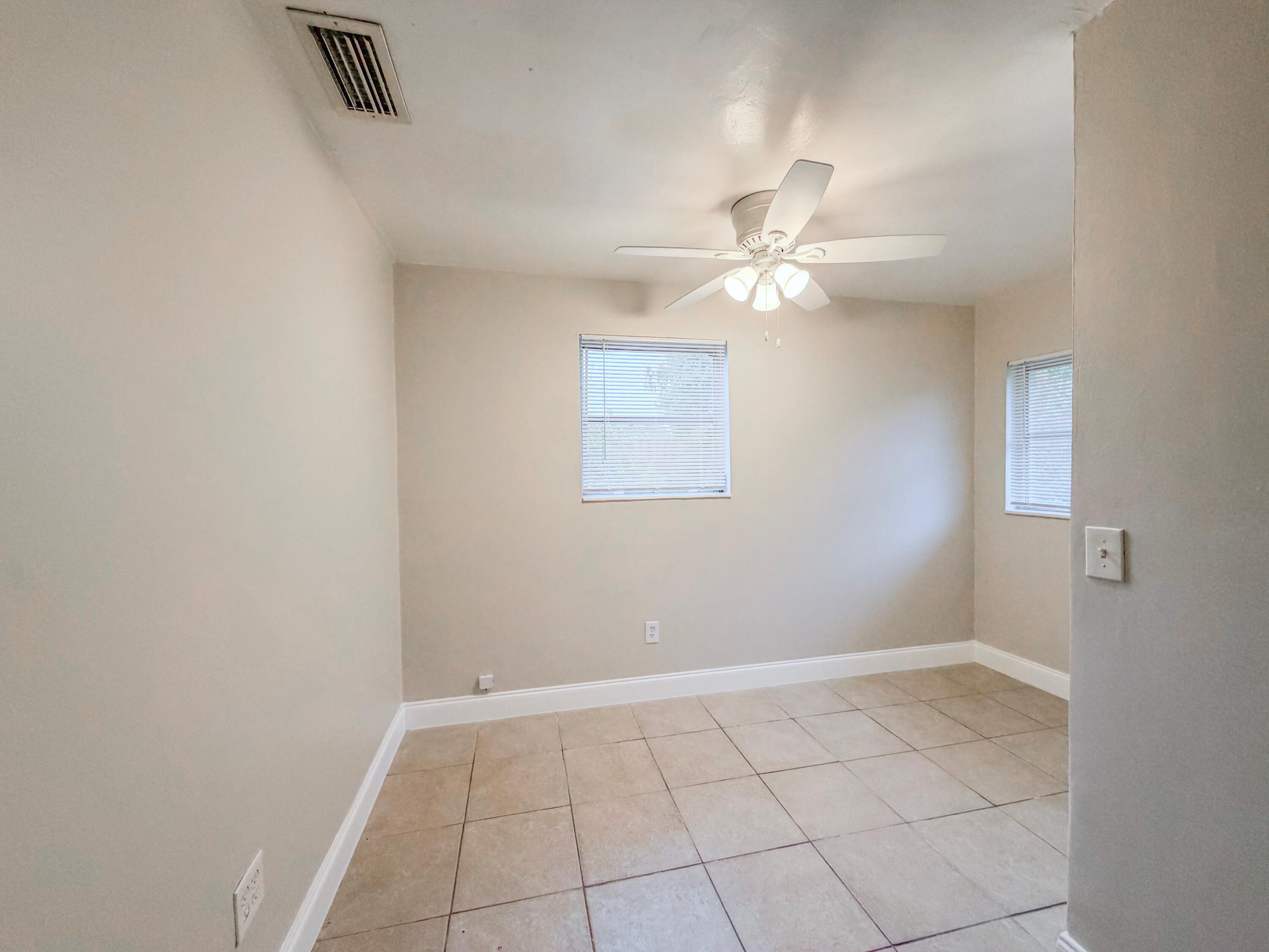 3077 Floweva Street Palm Springs, FL 33406 - Photo 8 of 12 an empty room with windows and fan