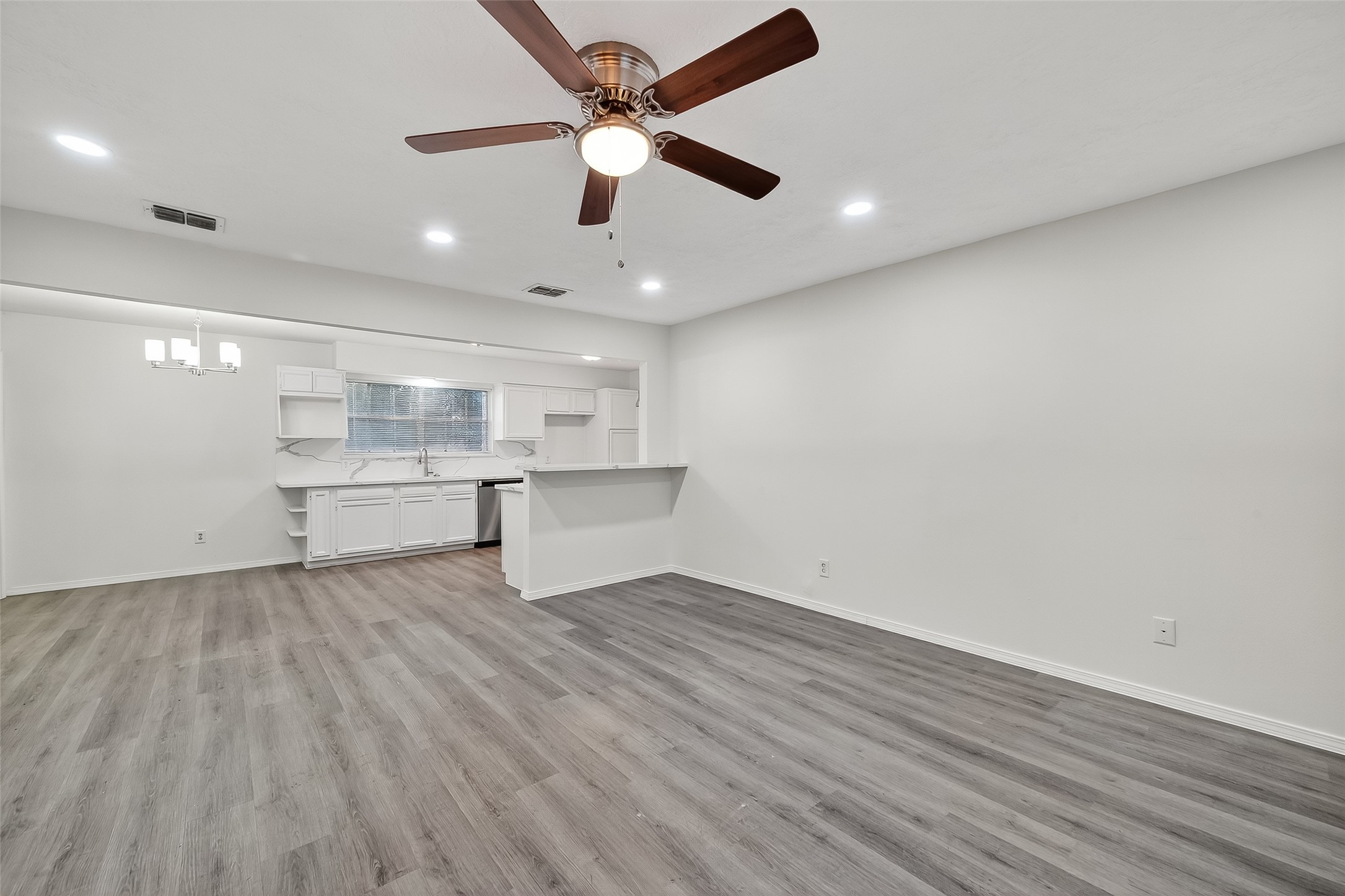 26522 Hillside Drive Spring, TX 77386 - Photo 11 of 45 an empty room with wooden floor a ceiling fan and kitchen view