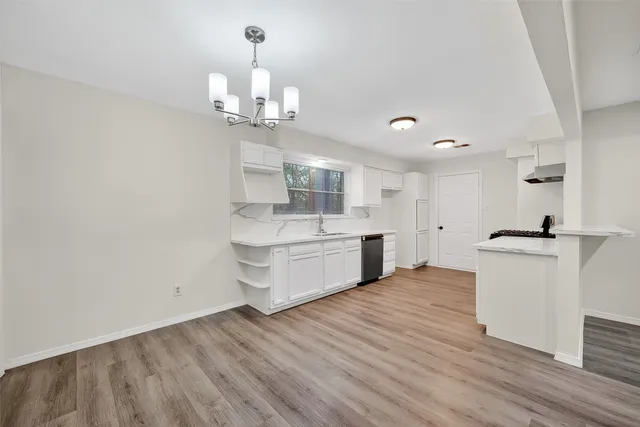 a large white kitchen with a white countertops a sink and a chandelier