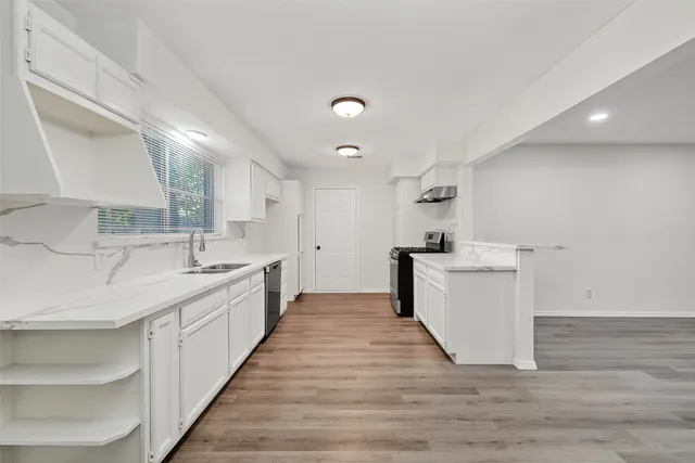a large white kitchen with a sink and dishwasher