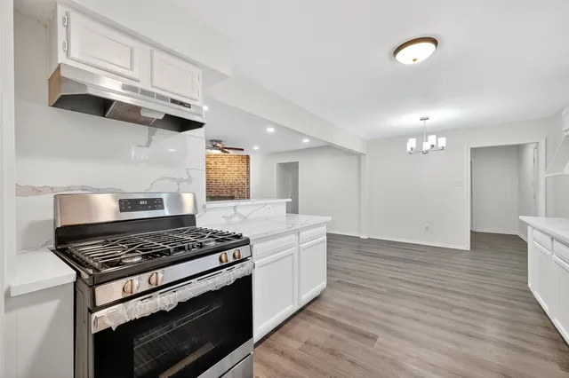 a kitchen with stainless steel appliances granite countertop a stove and a wooden floors