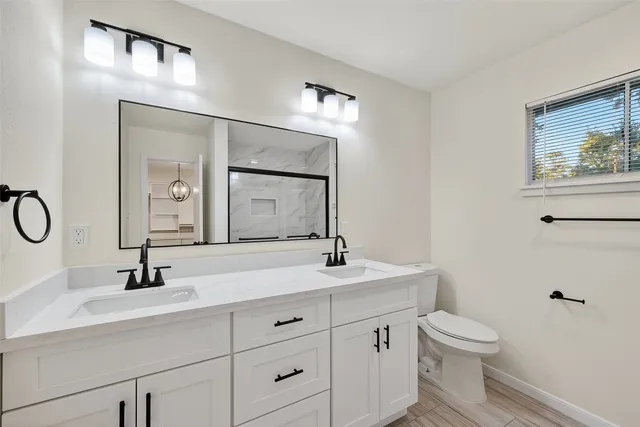 a bathroom with a toilet sink double vanity and mirror