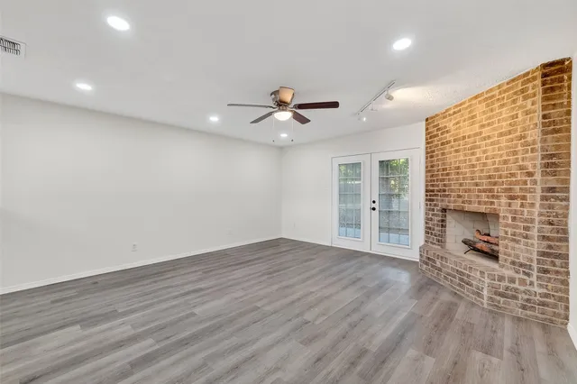an empty room with wooden floor and a ceiling fan