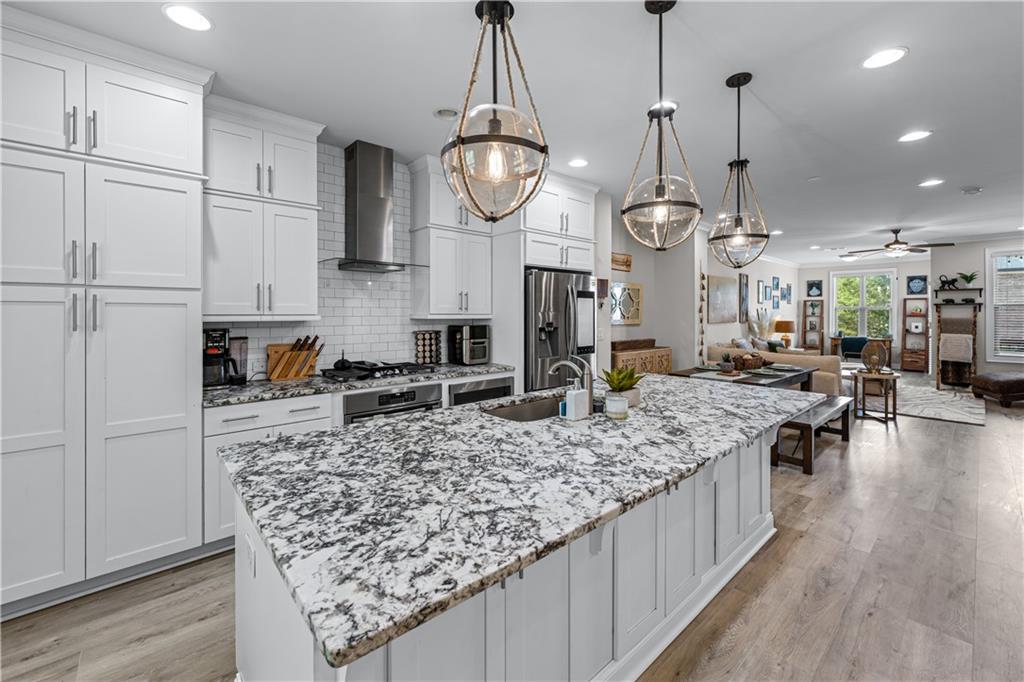 3766 Alstead Manor Way Suwanee, GA 30024 - Photo 6 of 41 a large kitchen with stainless steel appliances granite countertop a sink a stove and a wooden floors