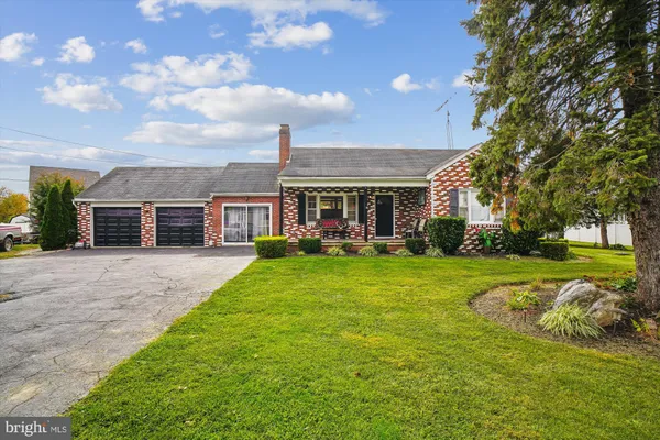 a view of house in front of a big yard with large trees
