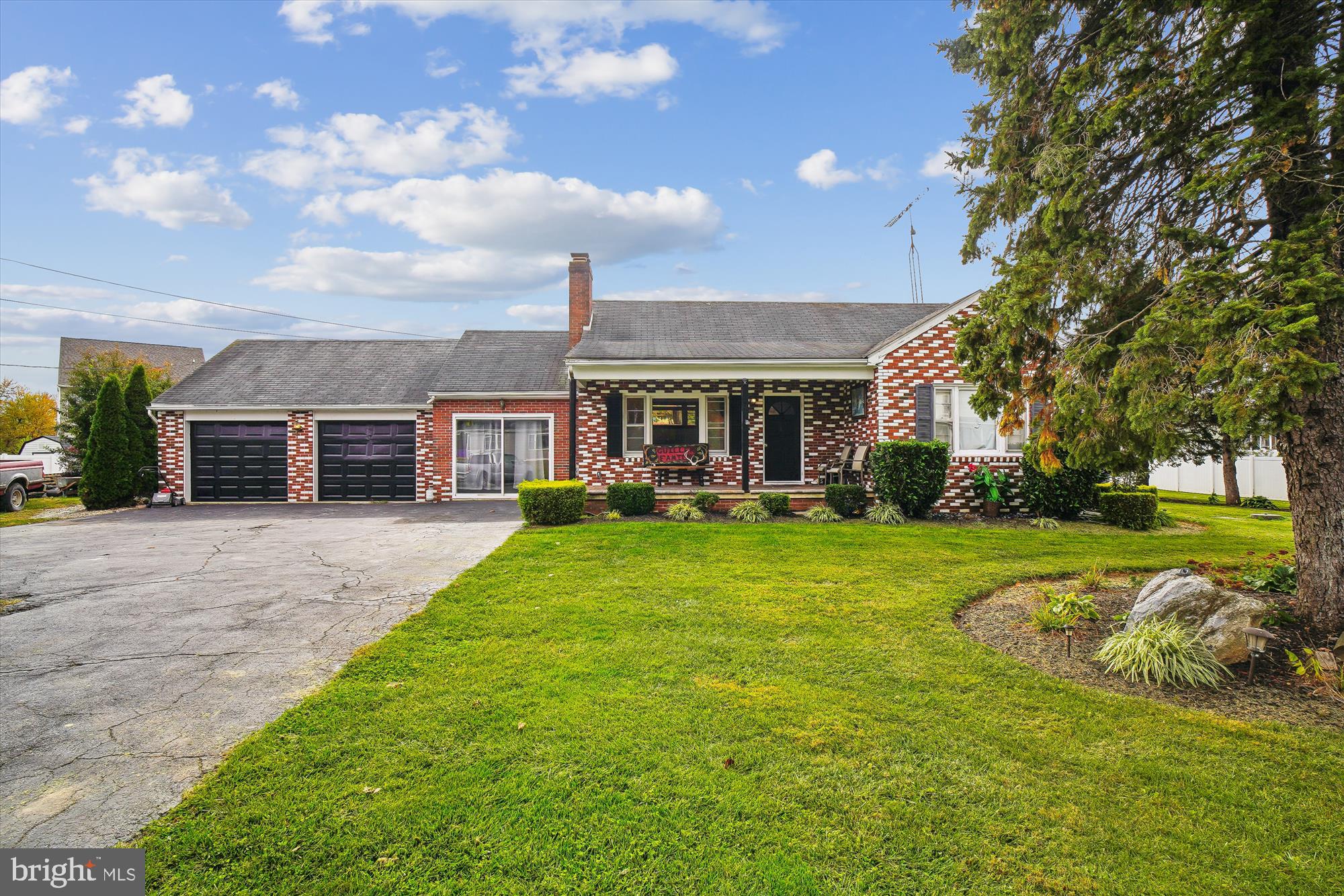 a view of house in front of a big yard with large trees