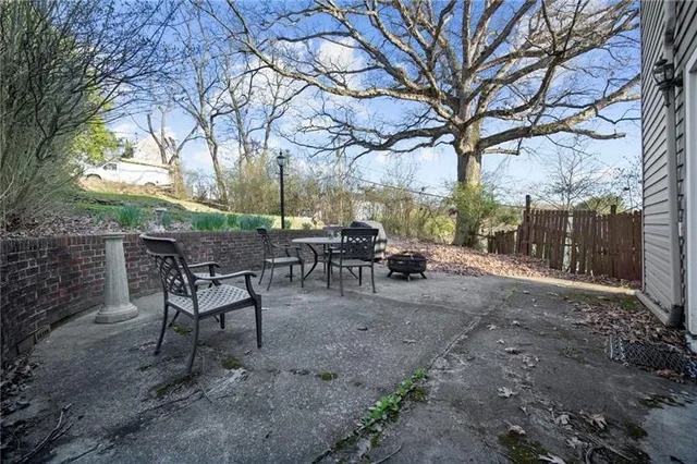 a view of a backyard with table and chairs and a barbeque with a large tree
