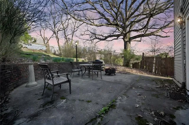 a view of a backyard with table and chairs potted plants and a large tree