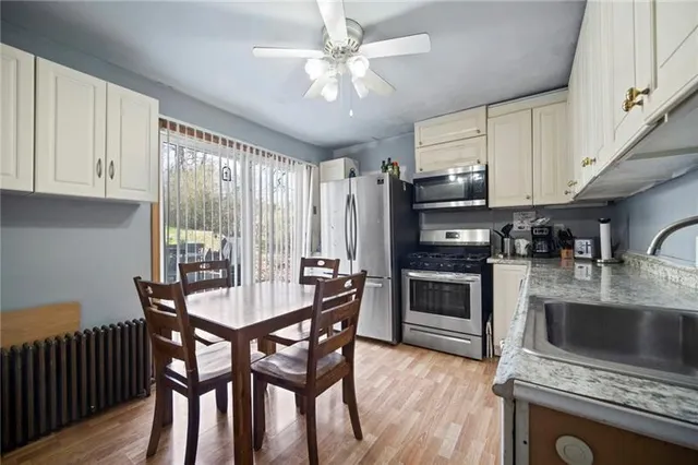 a kitchen with stainless steel appliances granite countertop a stove a sink a microwave a refrigerator cabinets and a dining table