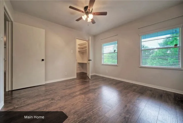 an empty room with wooden floor chandelier and windows
