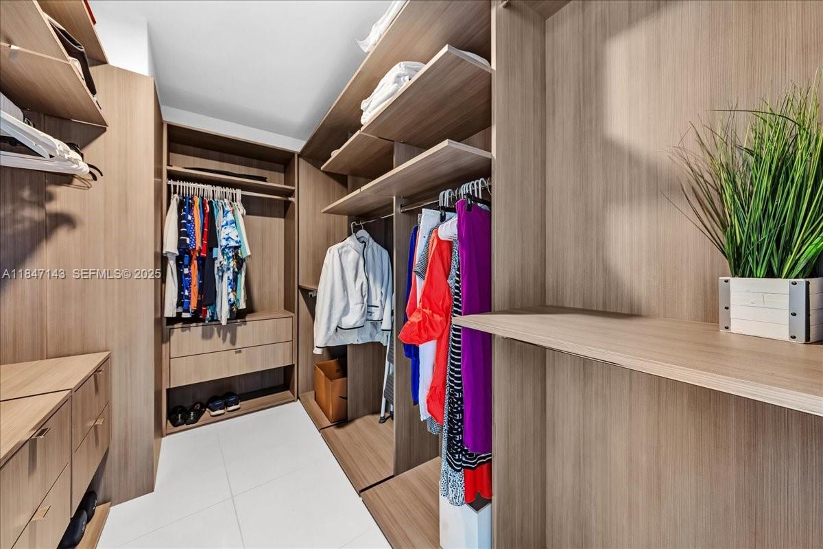 851 Northeast 1st Avenue, Unit 3711 Miami, FL 33132 - Photo 22 of 47 a view of walk in closet with clothes and shoes