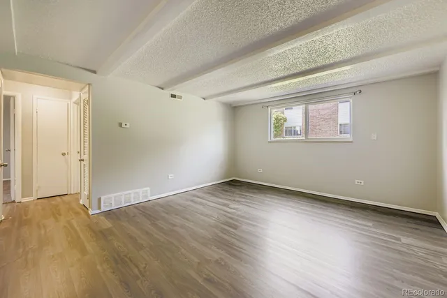 an empty room with wooden floor and windows
