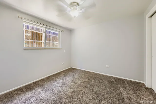 an empty room with a window and a ceiling fan