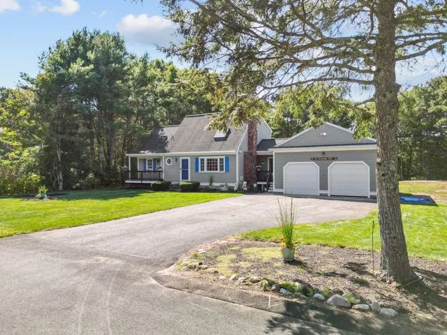 a front view of a house with a big yard and large tree