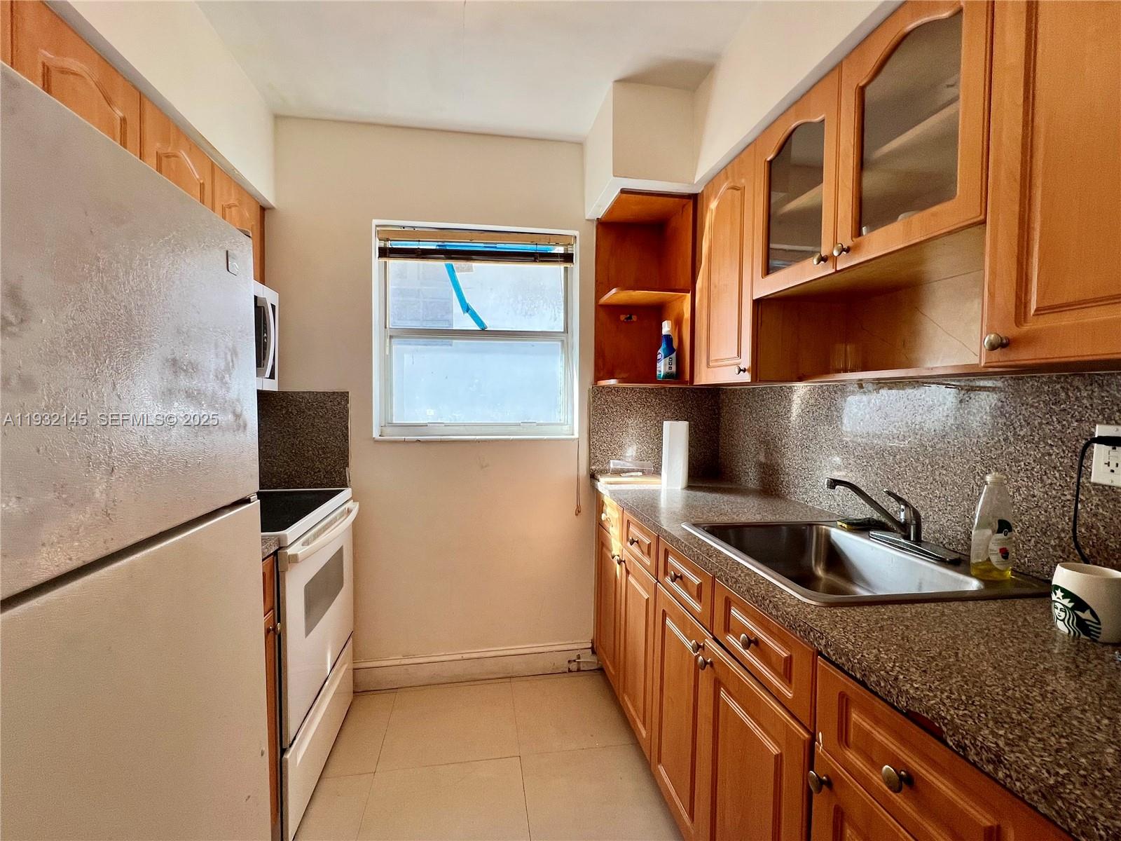 a kitchen with stainless steel appliances granite countertop a sink and a refrigerator