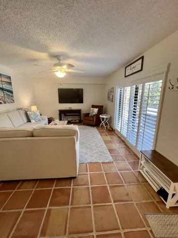 a living room with furniture a flat screen tv and a floor to ceiling window